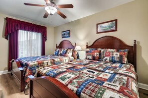 A bedroom with a wooden bed, a ceiling fan, a window with curtains, and a framed picture on the wall.