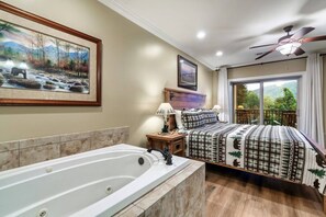 Un dormitorio con una cama grande, una bañera, un ventilador de techo y una ventana con vistas.
