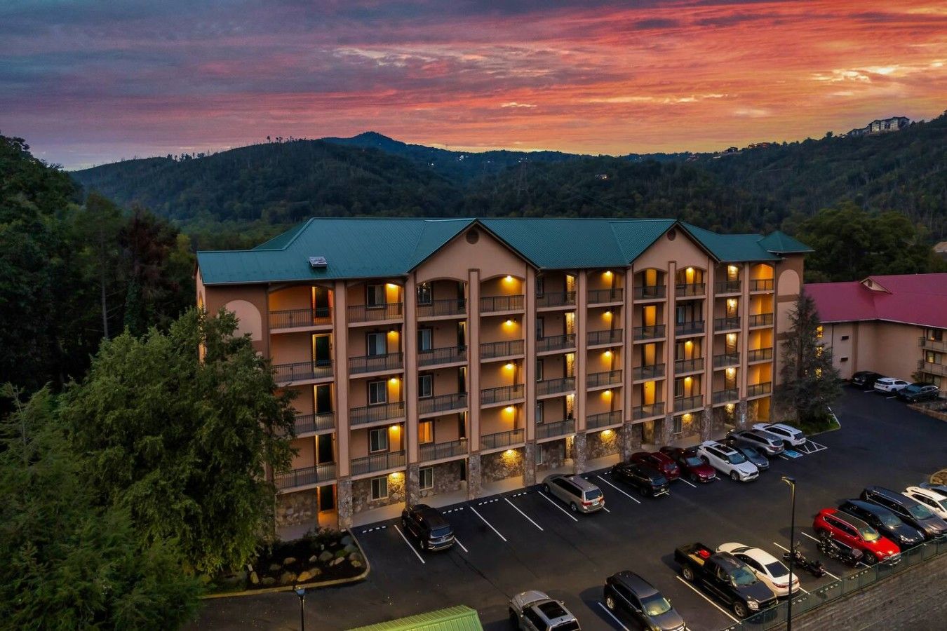 A multi-story hotel with a parking lot and a view of the surrounding hills.