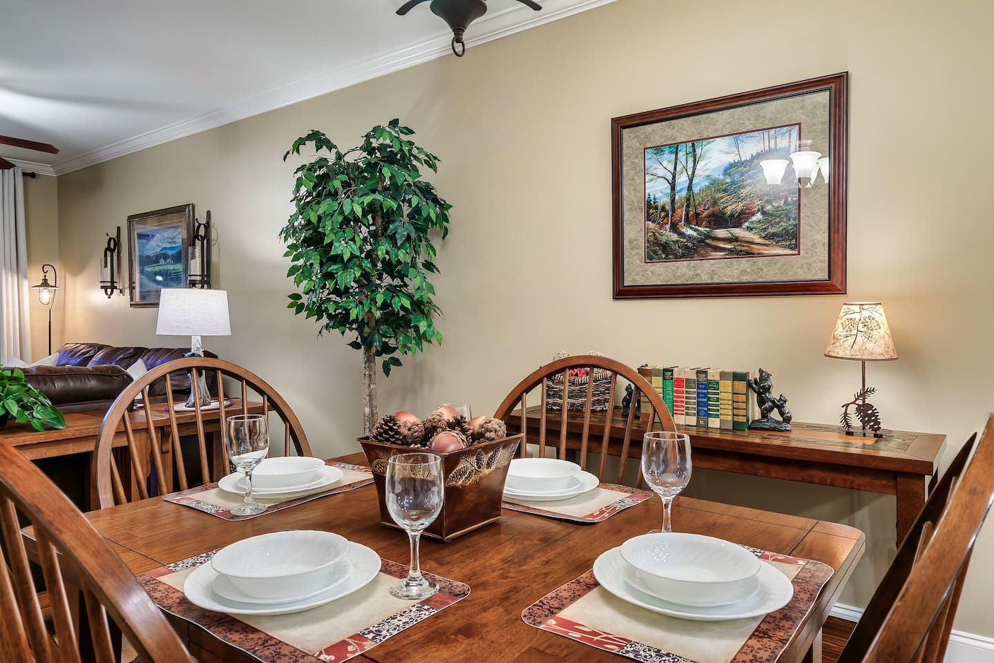 A dining room with a wooden table set for four, surrounded by chairs.