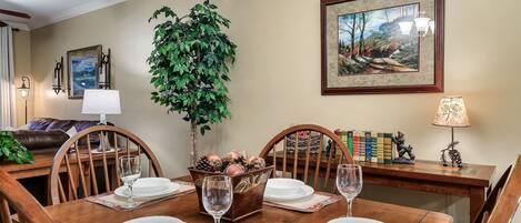 A dining room with a wooden table set for four, surrounded by chairs.