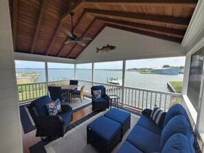 A covered outdoor seating area with a view of the water, featuring a table and chairs, a sofa, and a ceiling fan. - High Water Guest House<br> (Cambridge)
