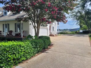 A single-story house with a porch, a tree with pink flowers, and a well-maintained lawn. - High Water Guest House<br> (Cambridge)