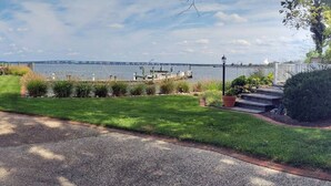 A residential property with a well-maintained lawn, a dock, and a view of a bridge across a body of water. - High Water Guest House<br> (Cambridge)