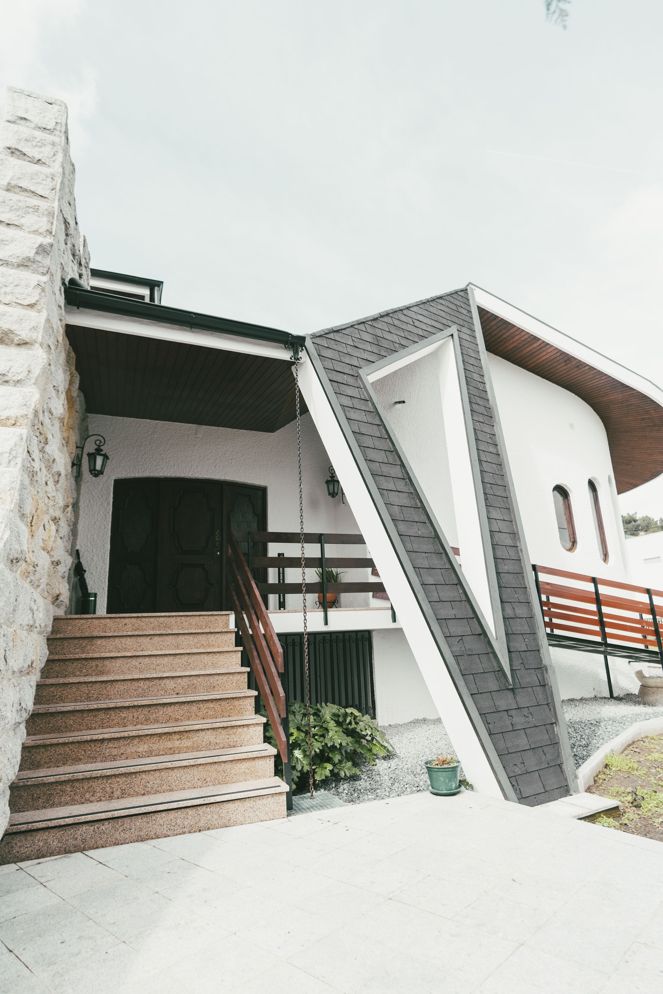 A modern house with a stone facade, a wooden staircase, and a unique angular design.