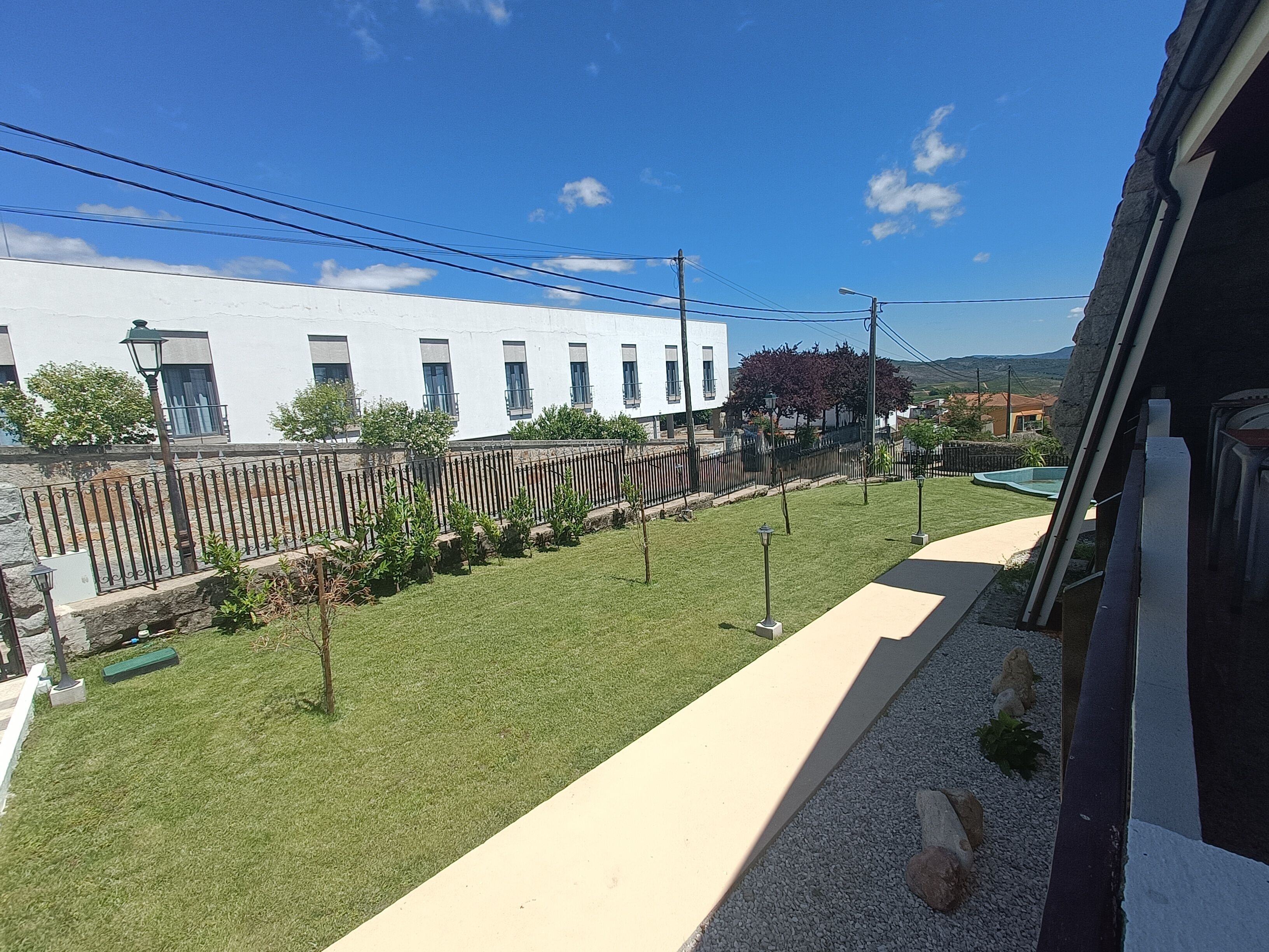 A residential area with a white building, a fenced yard, and a clear sky.