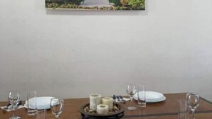 A dining table set for four with white plates, cutlery, and glasses, and a centerpiece of candles. - Elegant Blue 6 min From Airport ! (Mérida)