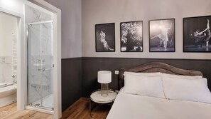 Experience a serene retreat with a glass-enclosed shower, a comfortable bed, and a stylish gallery wall.