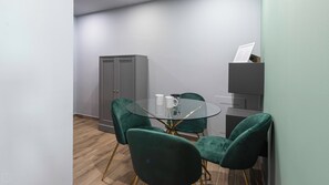 Conference room with a glass-top table and two chairs, featuring a neutral color palette and a wooden floor.