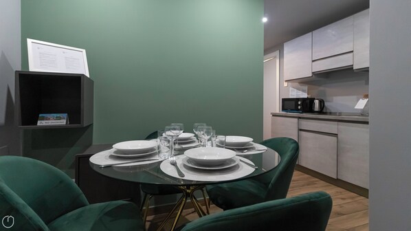 Guests can dine in style with a round table set for four, featuring fine china and cutlery.