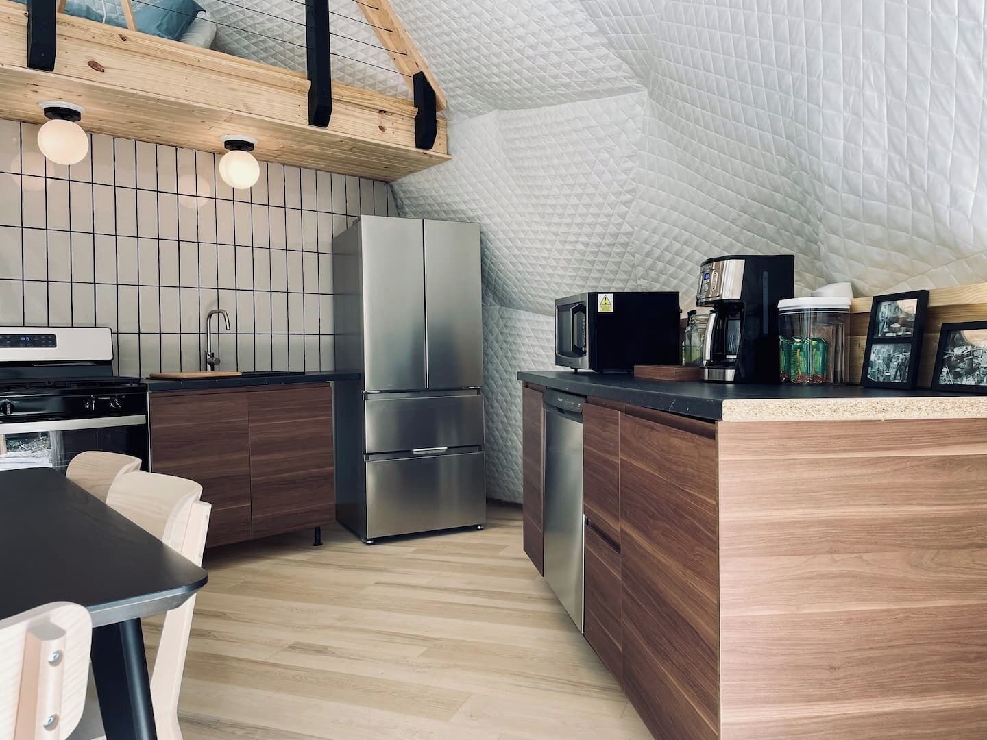 Una cocina moderna con techo de madera, estufa integrada, refrigerador y cafetera.