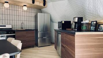 Una cocina moderna con techo de madera, estufa integrada, refrigerador y cafetera.