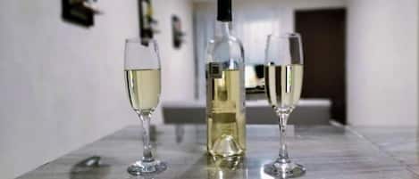 A marble table with a wine bottle and two glasses of white wine.
