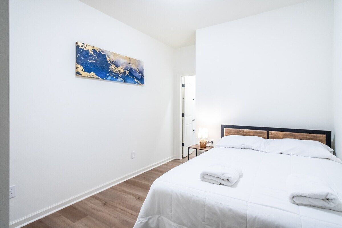 Una camera d'albergo con un letto, un comodino, una lampada e un quadro appeso al muro.