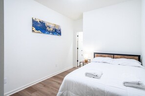A hotel room with a bed, a nightstand, a lamp, and a painting on the wall.