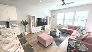 A modern living room with a television, sofa, ottoman, and coffee table.