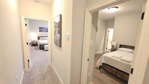 A hotel room with a bed, bedside table, lamp, and a painting on the wall. - Mardi Gras Magic Getaway in Baton Rouge  -  BC1019 (Baton Rouge)