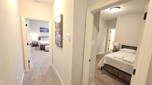 A hotel room with a bed, bedside table, lamp, and a painting on the wall.