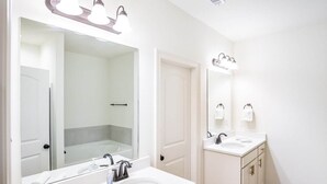 A bathroom with a large mirror, two sinks, and a shower area. - Mardi Gras Magic Getaway in Baton Rouge  -  BC1019 (Baton Rouge)