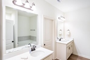 A bathroom with a large mirror, two sinks, and a shower area.