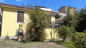 A yellow building with a tiled roof, surrounded by greenery and a clear blue sky. - Cottage - Sleeps 4 - Parking - Garden (Noto)