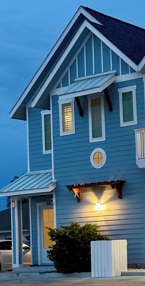 A two-story house with a blue exterior, a front porch, and a garage.