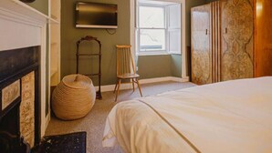 A bedroom with a bed, a television, a window, a fireplace, and a wardrobe. - TCN · The Crow's Nest, Pittenweem - Your Seaside Retreat (Pittenweem, Fife,)