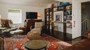 A cozy living room with a television, bookshelves, a chair, a sofa, and a patterned rug. - TCN · The Crow's Nest, Pittenweem - Your Seaside Retreat (Pittenweem, Fife,)
