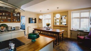 A modern kitchen with a wooden countertop, a dining table, and a large window providing natural light. - TCN · The Crow's Nest, Pittenweem - Your Seaside Retreat (Pittenweem, Fife,)