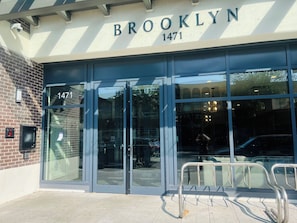 The exterior of a building with the name 'BROOKLYN' and the number '1471' displayed above the entrance.