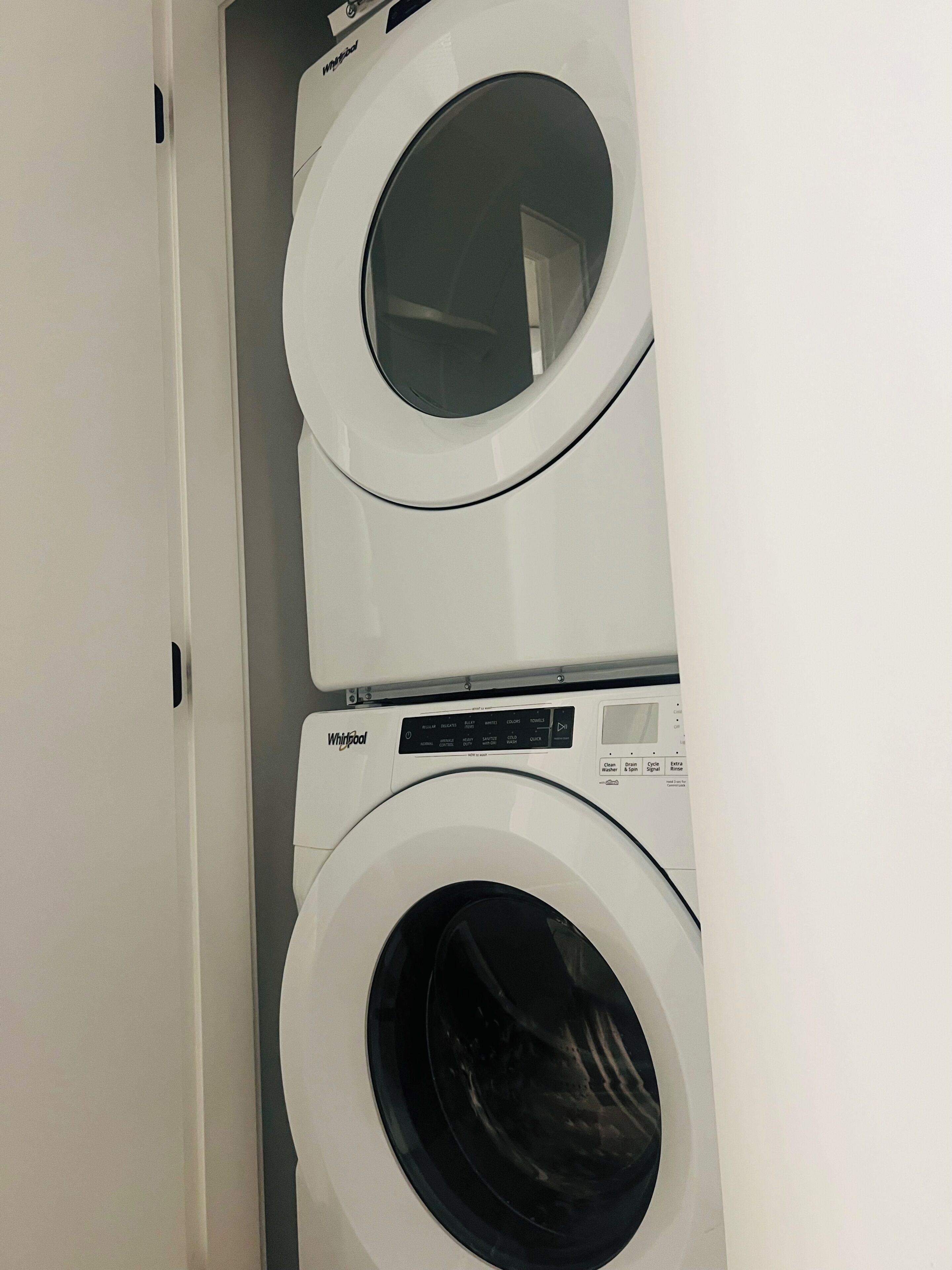 Een gestapelde wasmachine en droger met bedieningspanelen.