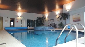 An indoor swimming pool with a tiled floor, a wooden ceiling, and a bench along one side. - 14 Burgh Island Causeway (Kingsbridge)