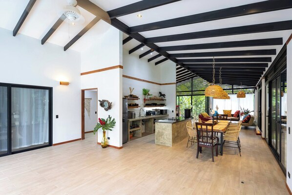 A spacious kitchen with modern appliances, a dining area with a large table and chairs, and a ceiling with exposed beams.