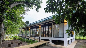 A modern house with a covered porch, large windows, and a garden area. - Casa Kali - 4-Min Walk to Beach - AC & Pool (Puerto Viejo de Talamanca)