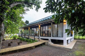 A modern house with a covered porch, large windows, and a garden area.