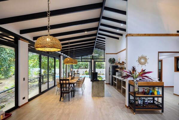 A modern kitchen with a large island, wooden flooring, and a view of the outdoors.