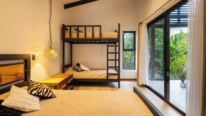 A room with a bunk bed, a desk, a hanging light fixture, and a large window with a view of greenery. - Casa Kali - 4-Min Walk to Beach - AC & Pool (Puerto Viejo de Talamanca)