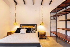 A bedroom with a bed, bedside tables, hanging lamps, and a built-in shelving unit.