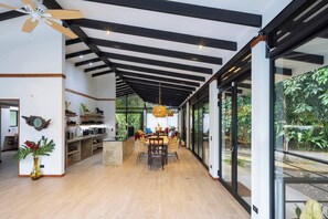 A modern kitchen with a central island, wooden beams, and large windows.