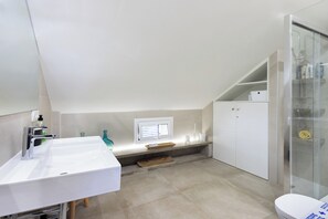 A modern bathroom with a white sink, a glass shower enclosure, and a toilet.