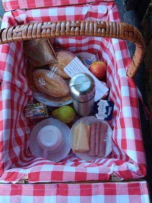 Ein Picknickkorb mit Brot, Äpfeln, einer Flasche, einer Zitrone und Butter.