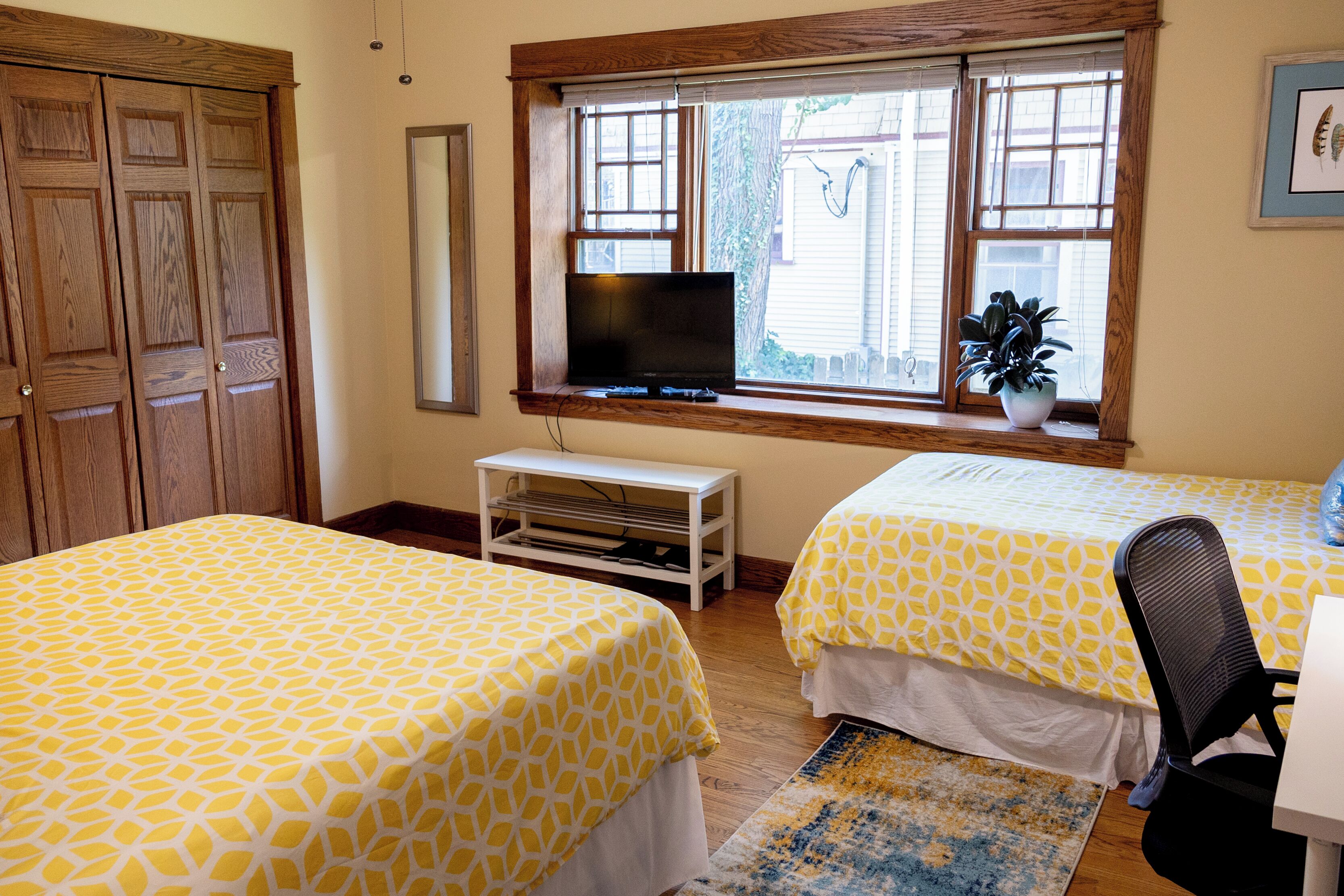 Un dormitorio con dos camas, televisión, escritorio y ventana con persianas.
