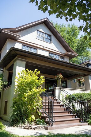 A two-story house with a front porch, a staircase, and a small garden area.