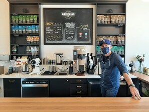 A coffee shop interior with a menu board, coffee machines, and shelves stocked with coffee products.