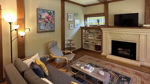 Un salon comprenant un canapé, des fauteuils, une table basse, une cheminée et un téléviseur.