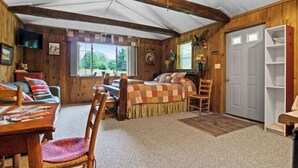 Une pièce confortable avec un lit, un bureau et une chaise. Il y a une fenêtre donnant sur des arbres.