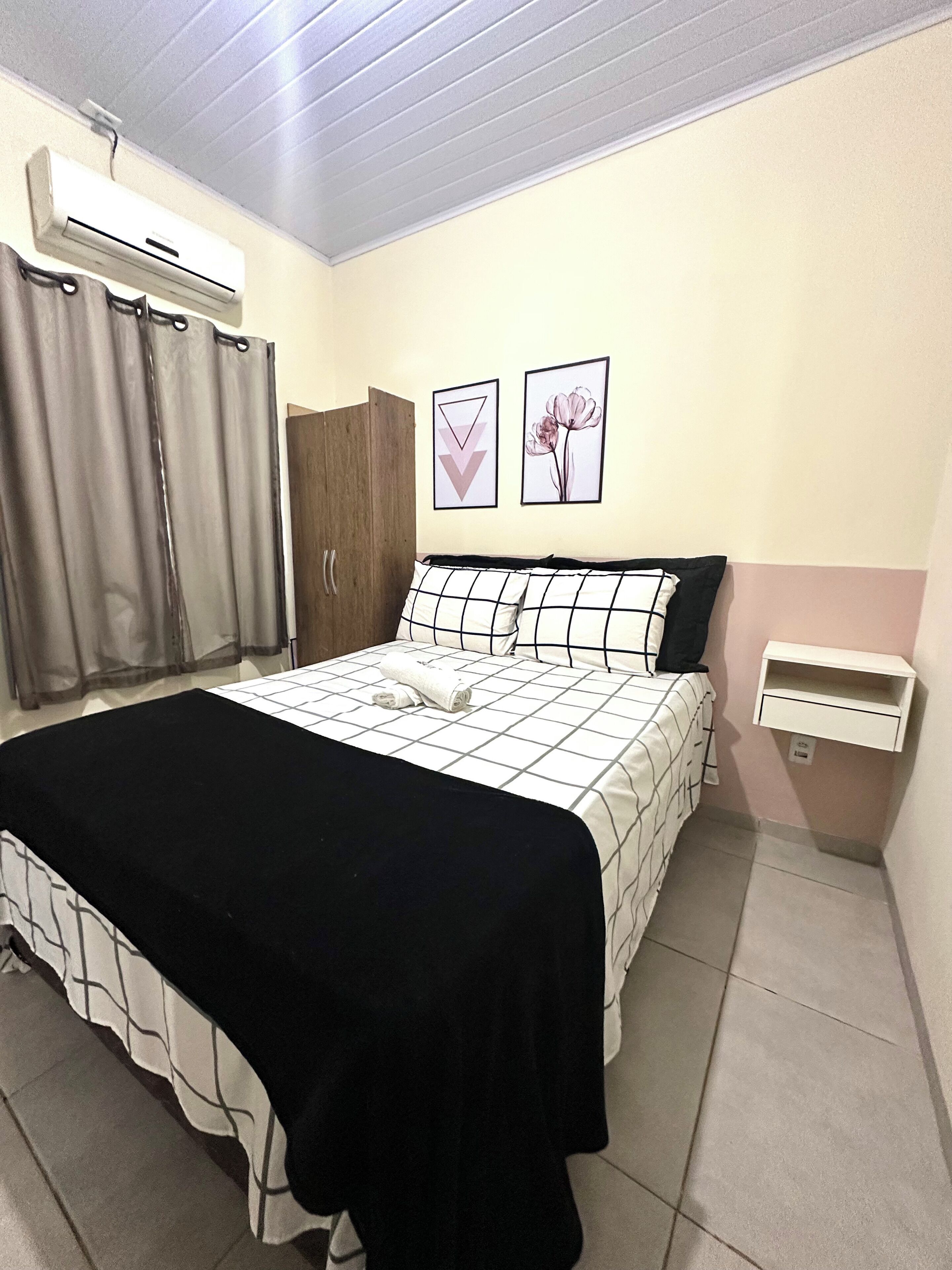 A bedroom with a bed, a nightstand, a wardrobe, and a wall-mounted air conditioner.