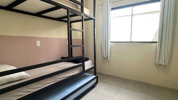 Dormitorio con literas, ventana y aire acondicionado.