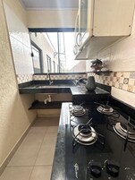A compact kitchen with a gas stove, a sink, and a window overlooking a street.