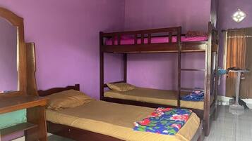 A room with two bunk beds, a wooden desk, and a mirror.